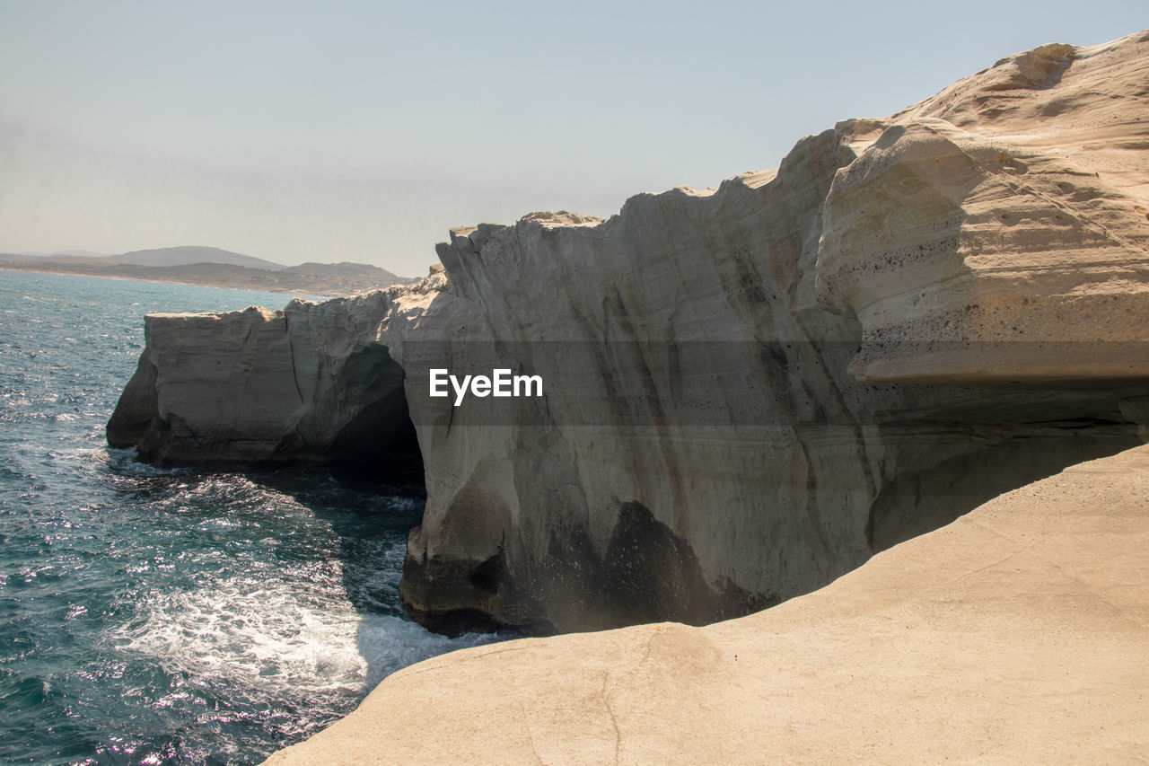 Rock formations by sea against sky