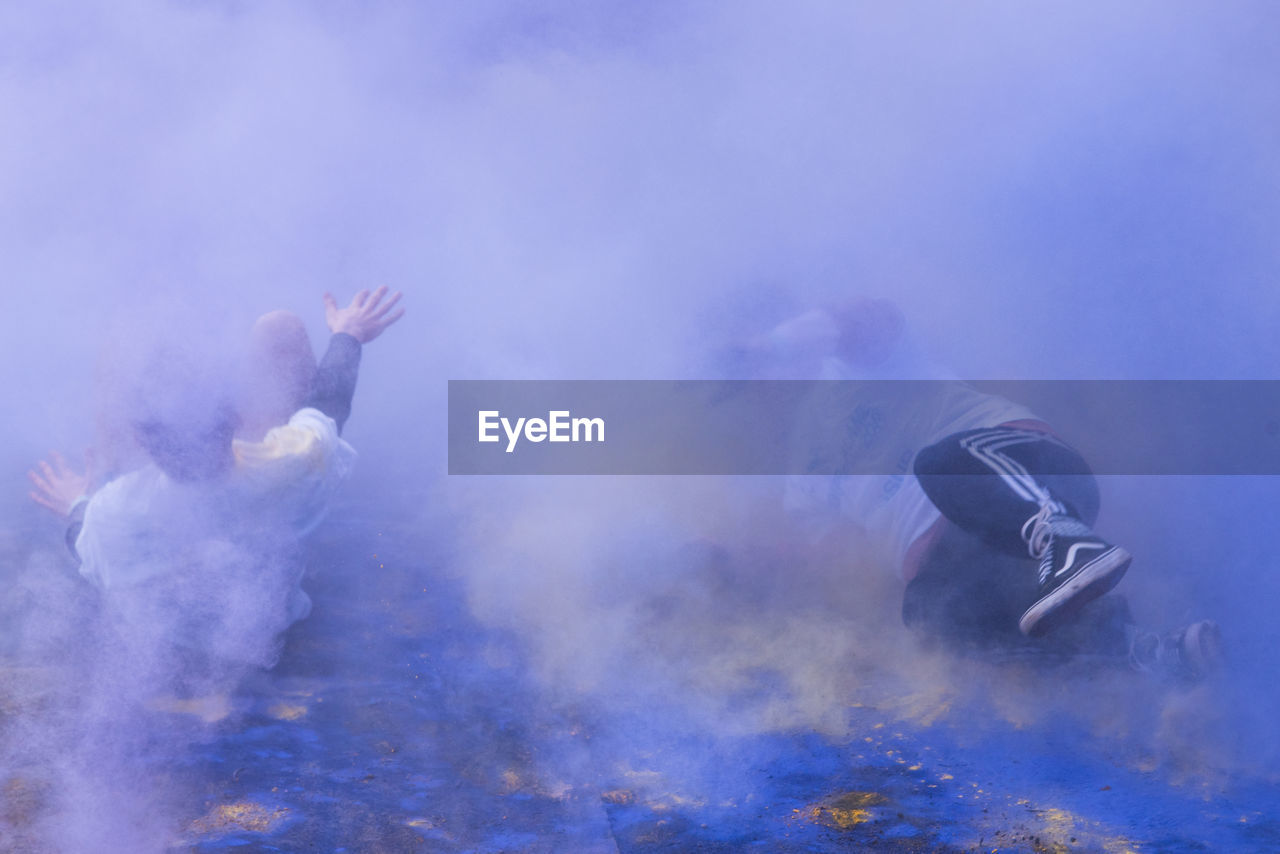 People enjoying amidst purple powder paint during holi