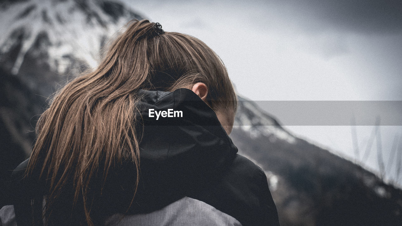 Rear view of woman with brown hair against snowcapped mountain