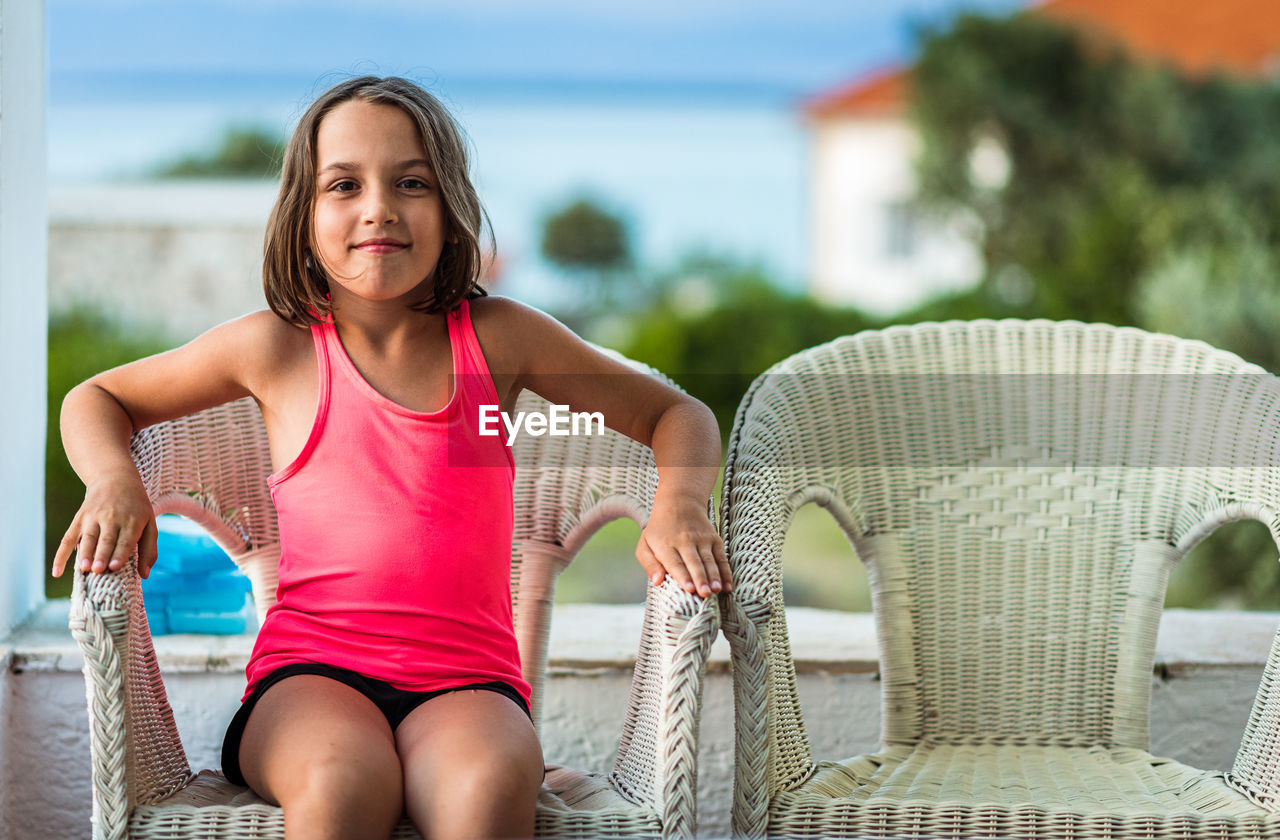 PORTRAIT OF SMILING GIRL SITTING ON SEAT