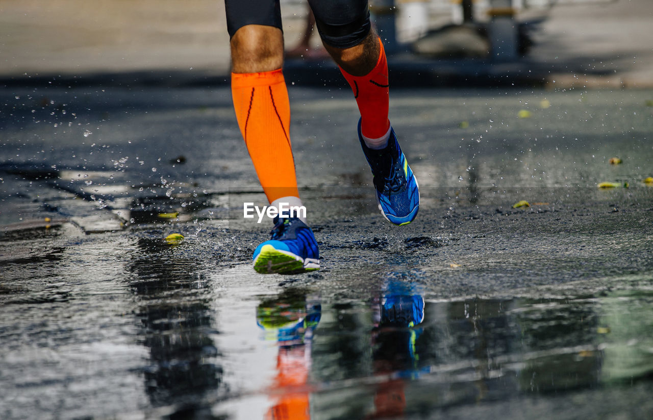 Legs male athlete in compression socks running on wet road