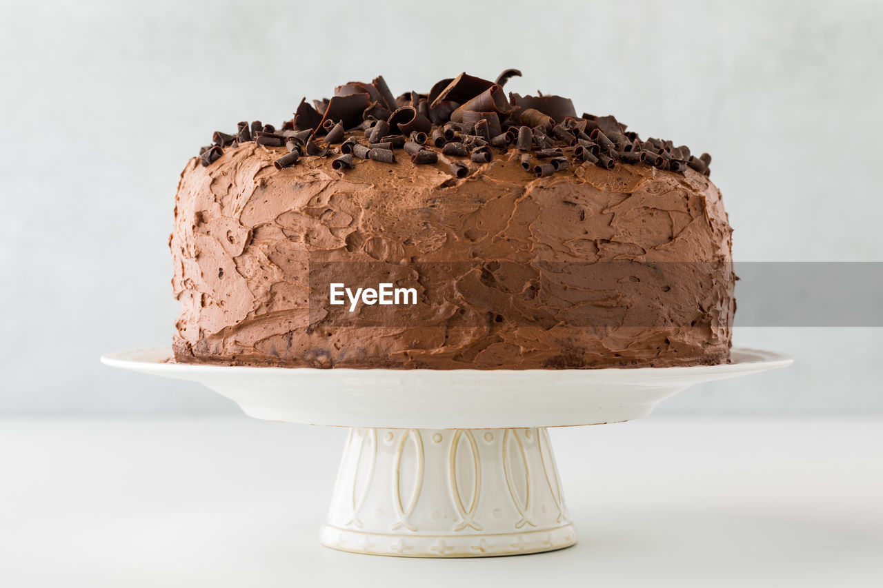 A whole triple layered low sugar chocolate cake on a pedestal stand.