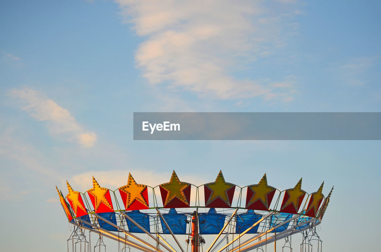 Low angle view of amusement park colorful carousel against sky