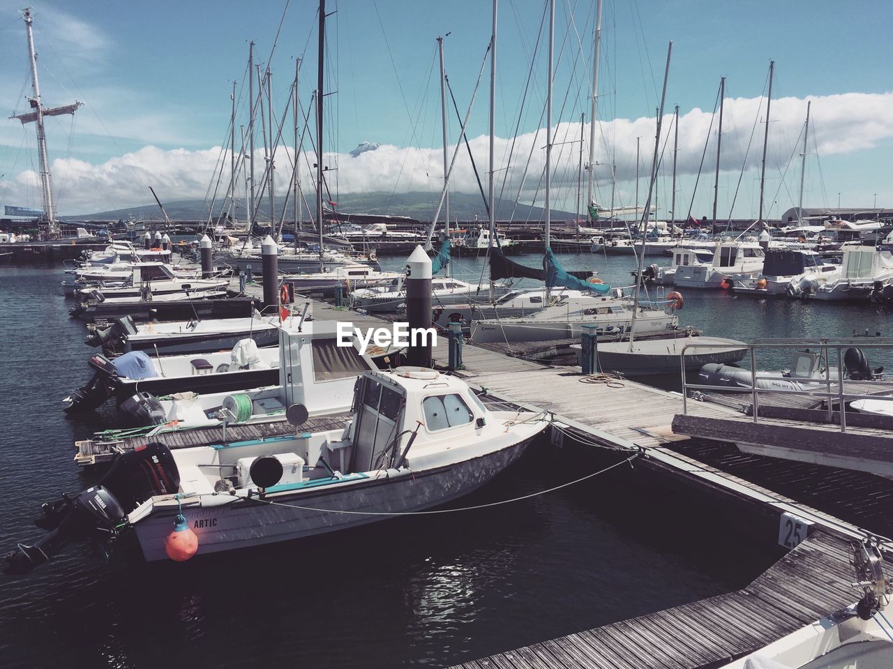 SAILBOATS MOORED IN HARBOR AGAINST SKY