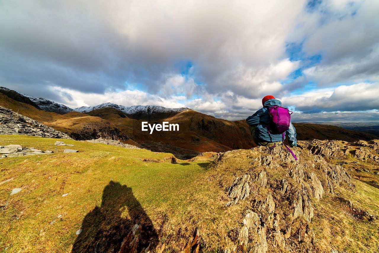 WOMAN STANDING ON FIELD AGAINST CLOUDY SKY