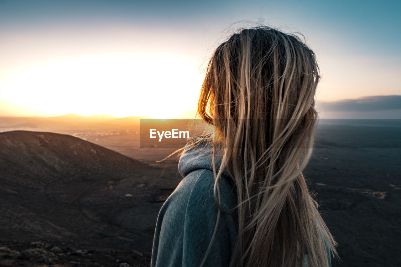 Side view of woman looking at landscape during sunset