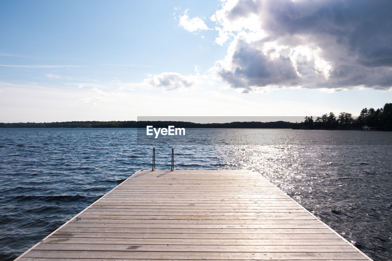 Pier over lake, water against sky.