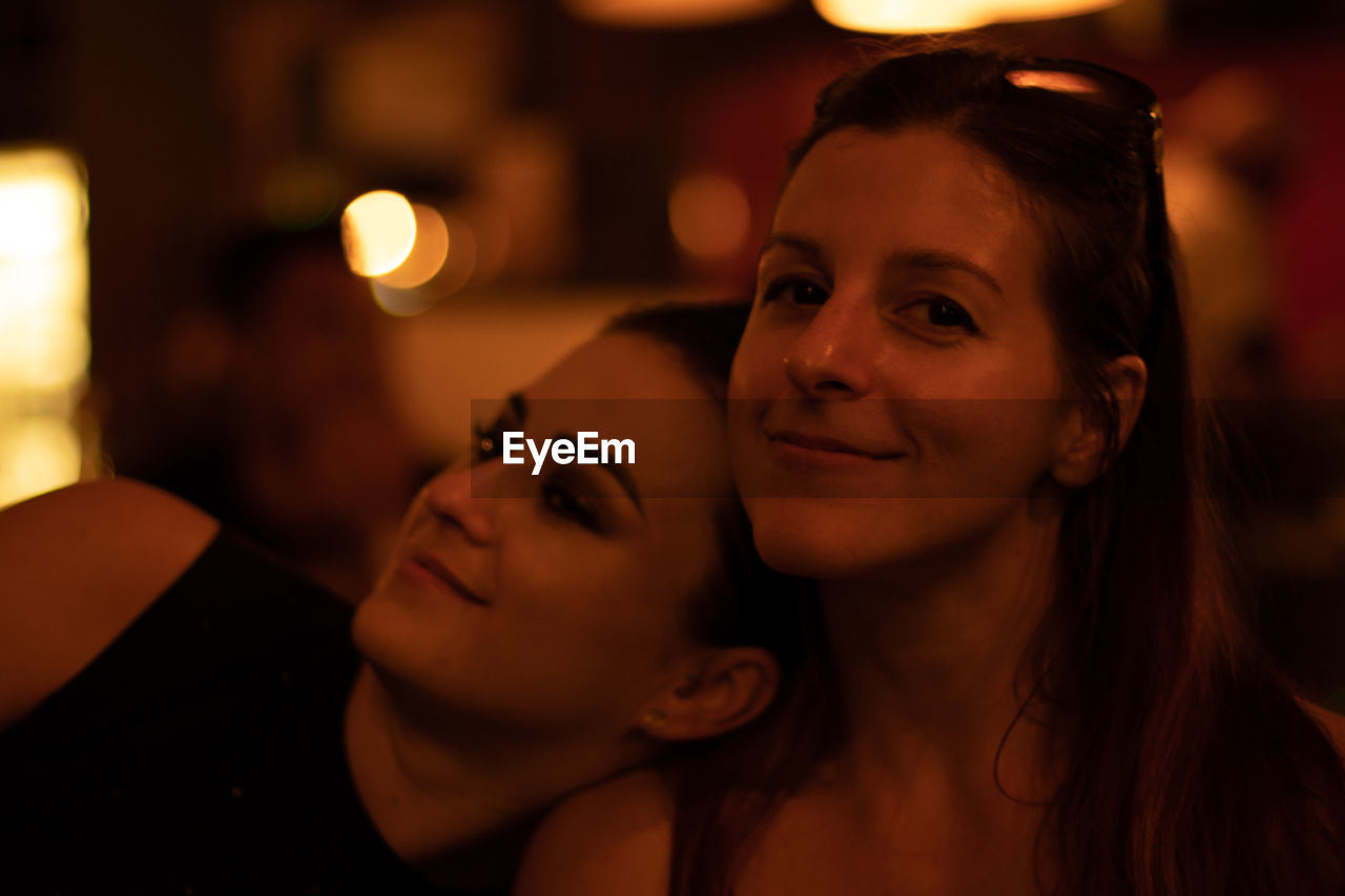 Portrait of smiling woman with friend in city at night