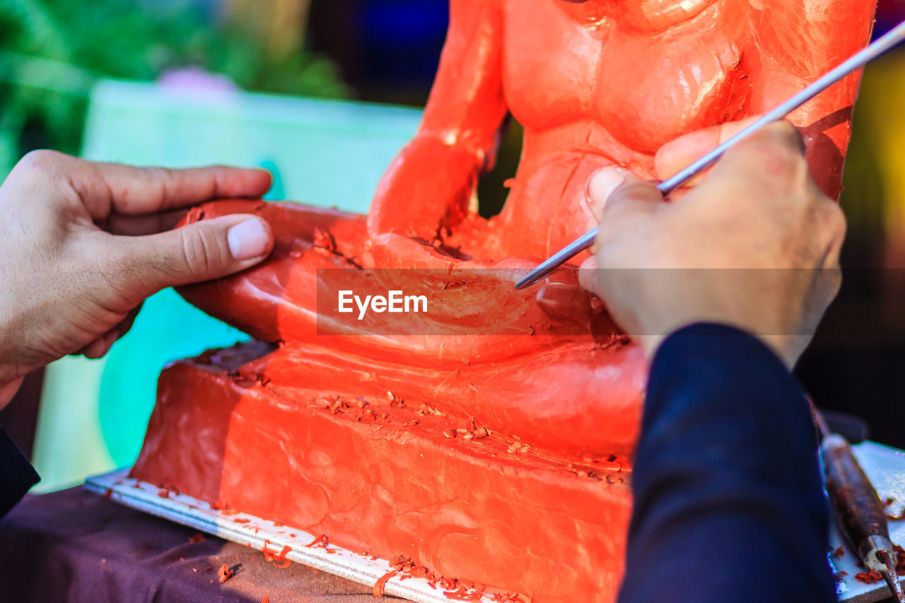 Cropped image of sculptor painting statue