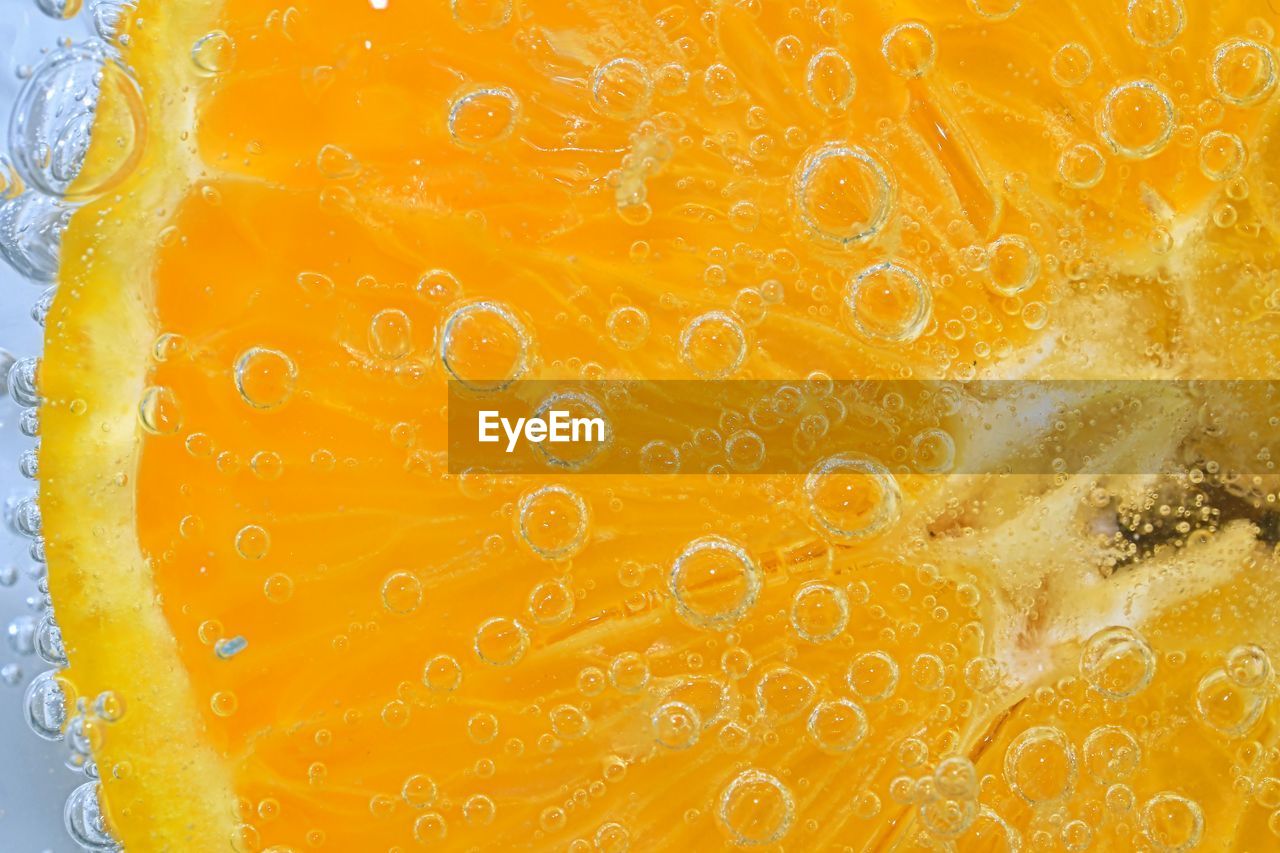 Slice of orange fruit in sparkling water. orange fruit slice covered by bubbles in carbonated water