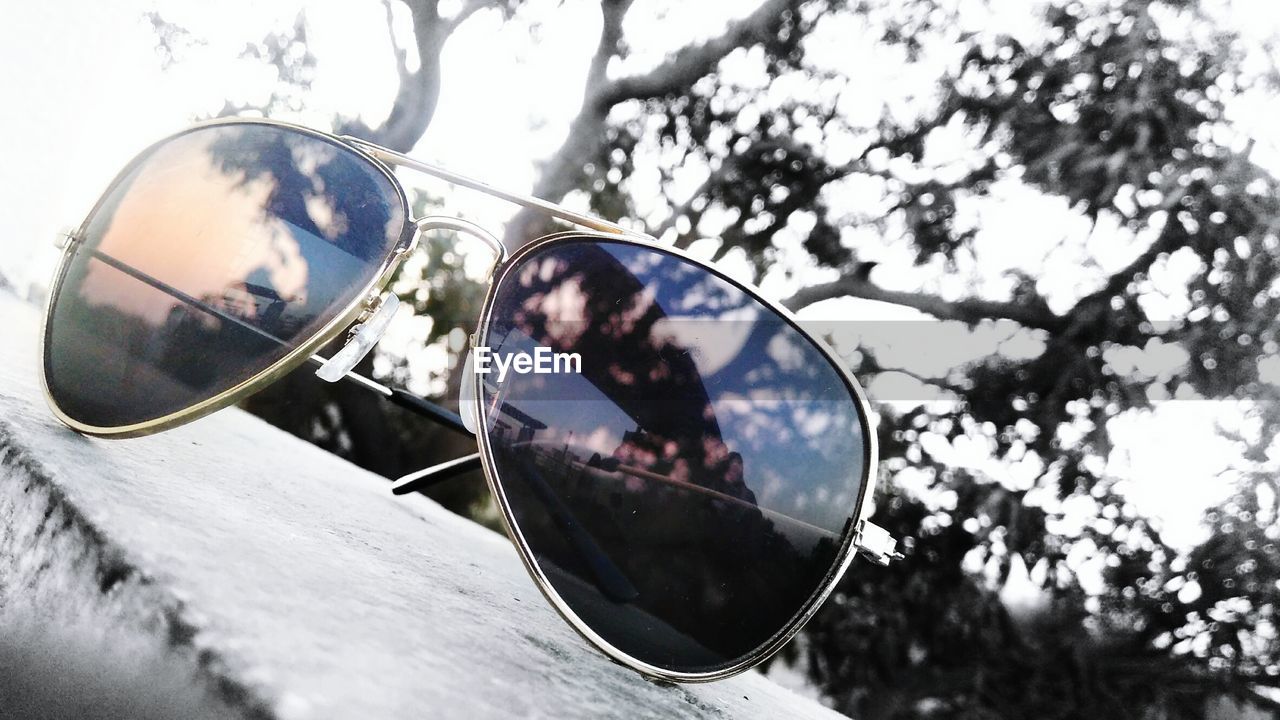 Close-up of sunglasses on retaining wall by trees