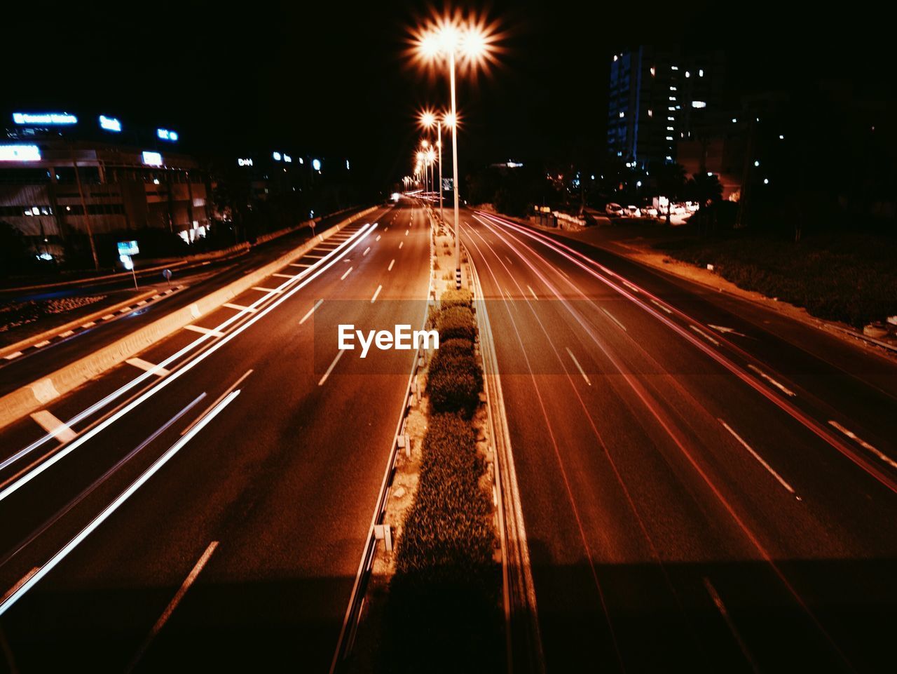 ROAD PASSING THROUGH ILLUMINATED CITY AT NIGHT