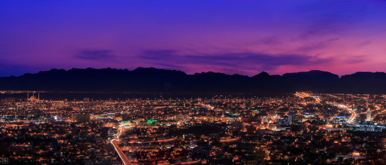 Aerial view of illuminated cityscape against sky at sunset