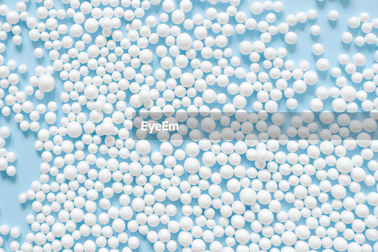 Abstract background consisting of spheres of white color on blue paper top view. minimal arrangement