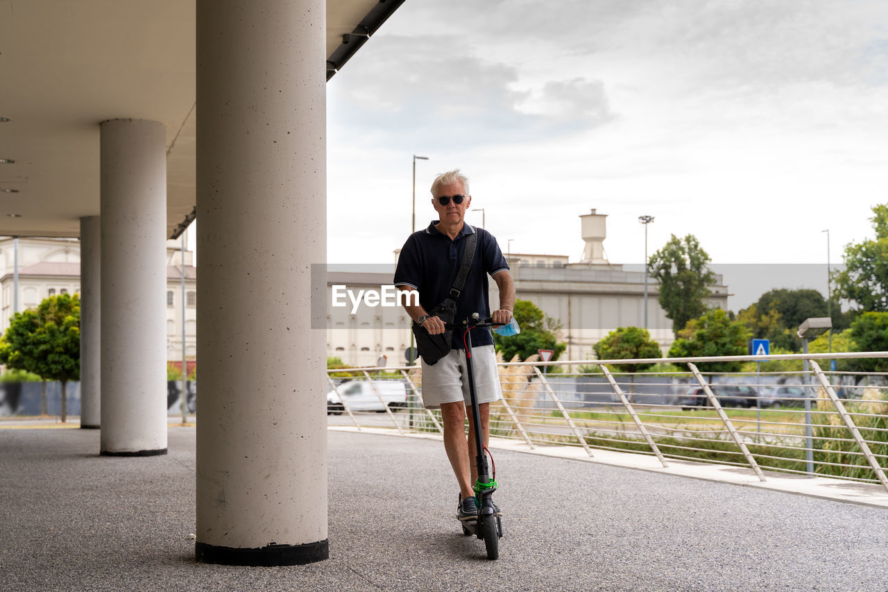 Commuter hipster man is using electric scooter on the outskirts of a city. eco transport concept