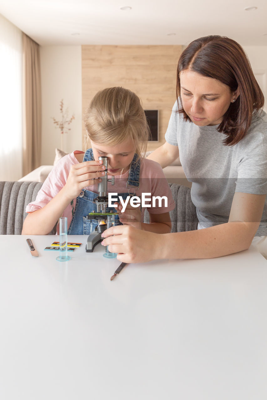 Mother helping daughter in science project at home