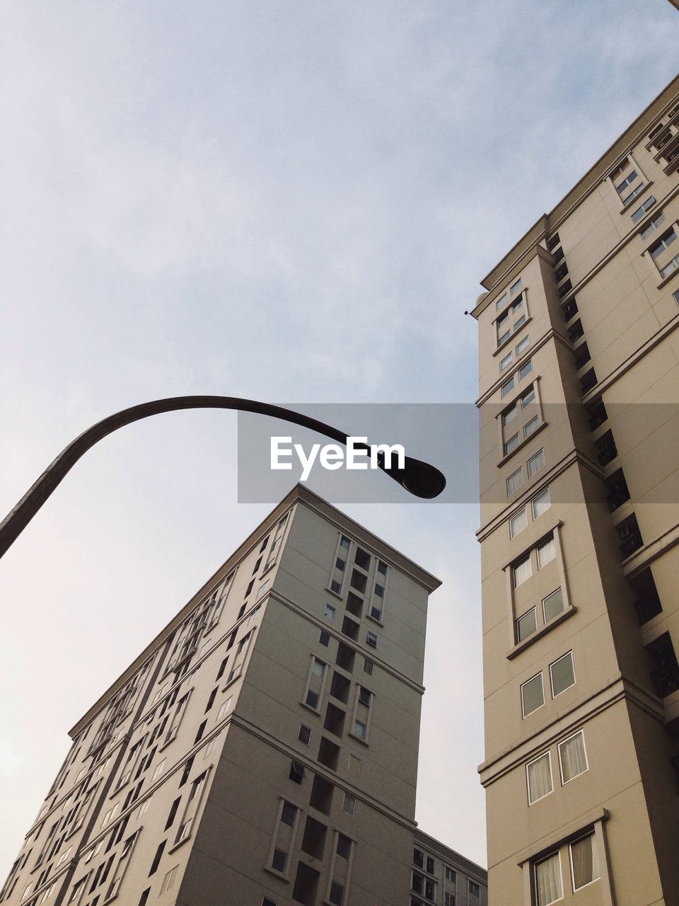 Low angle view of street light by building against sky