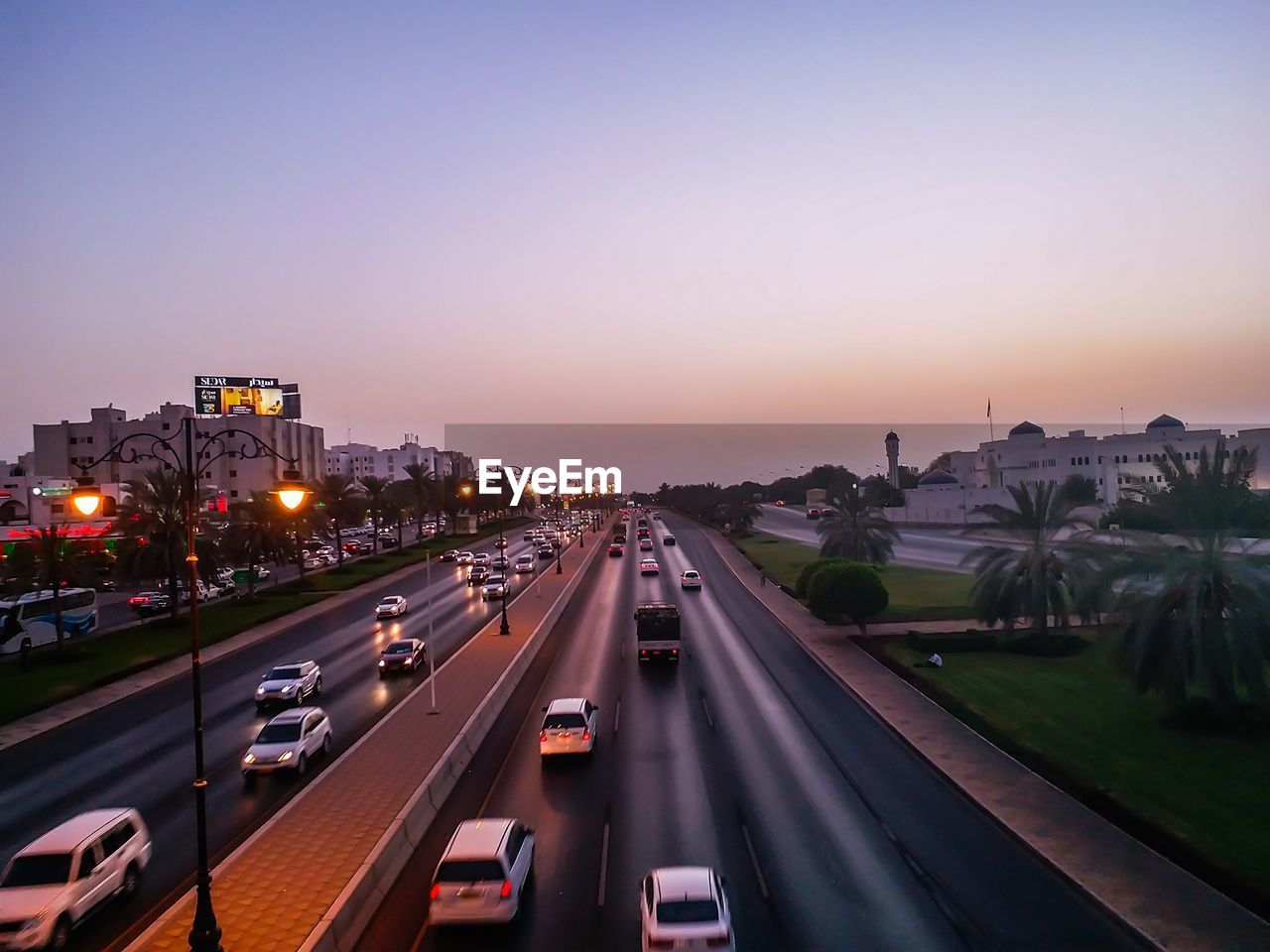 VEHICLES ON HIGHWAY IN CITY AGAINST CLEAR SKY