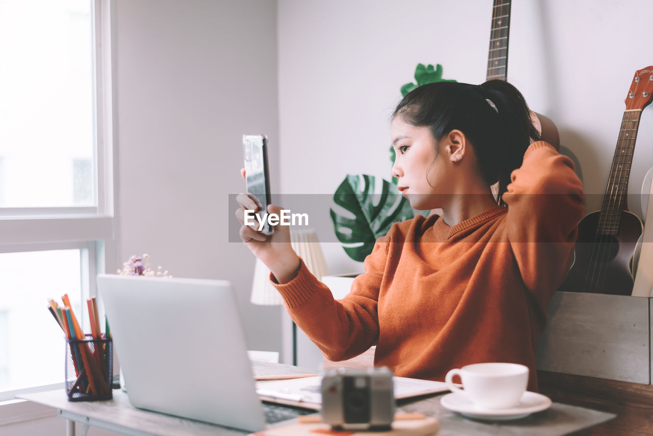 Woman using laptop while sitting on table