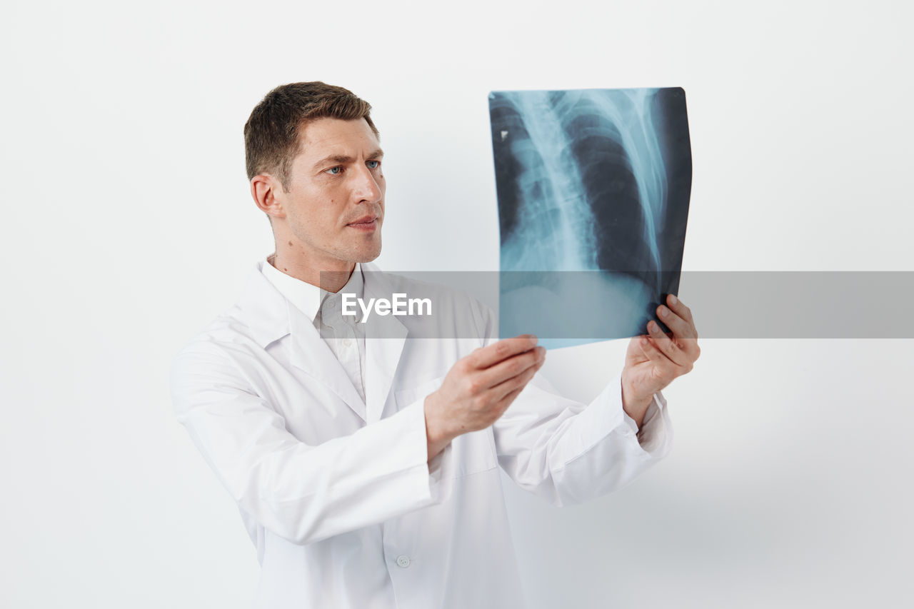 portrait of female doctor holding stethoscope against white background