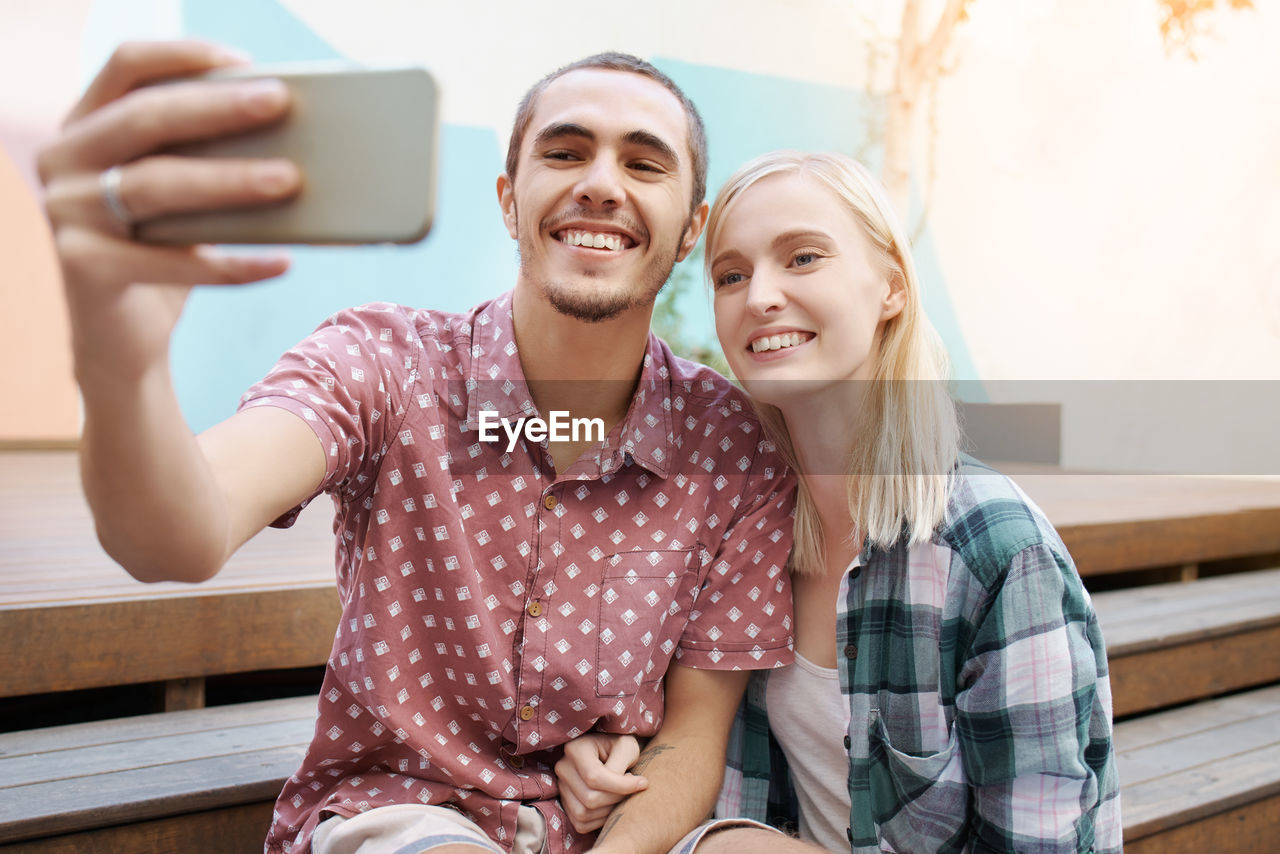 Smiling man taking selfie with girlfriend