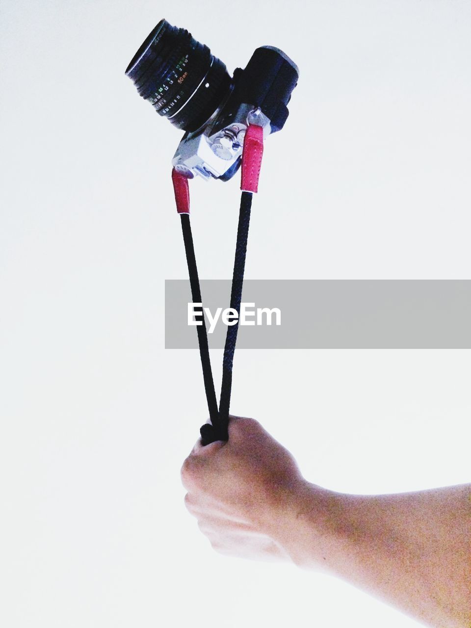 Close-up of hand holding camera against white background