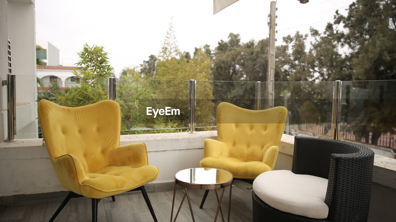 EMPTY CHAIRS AND TABLES AGAINST PLANTS