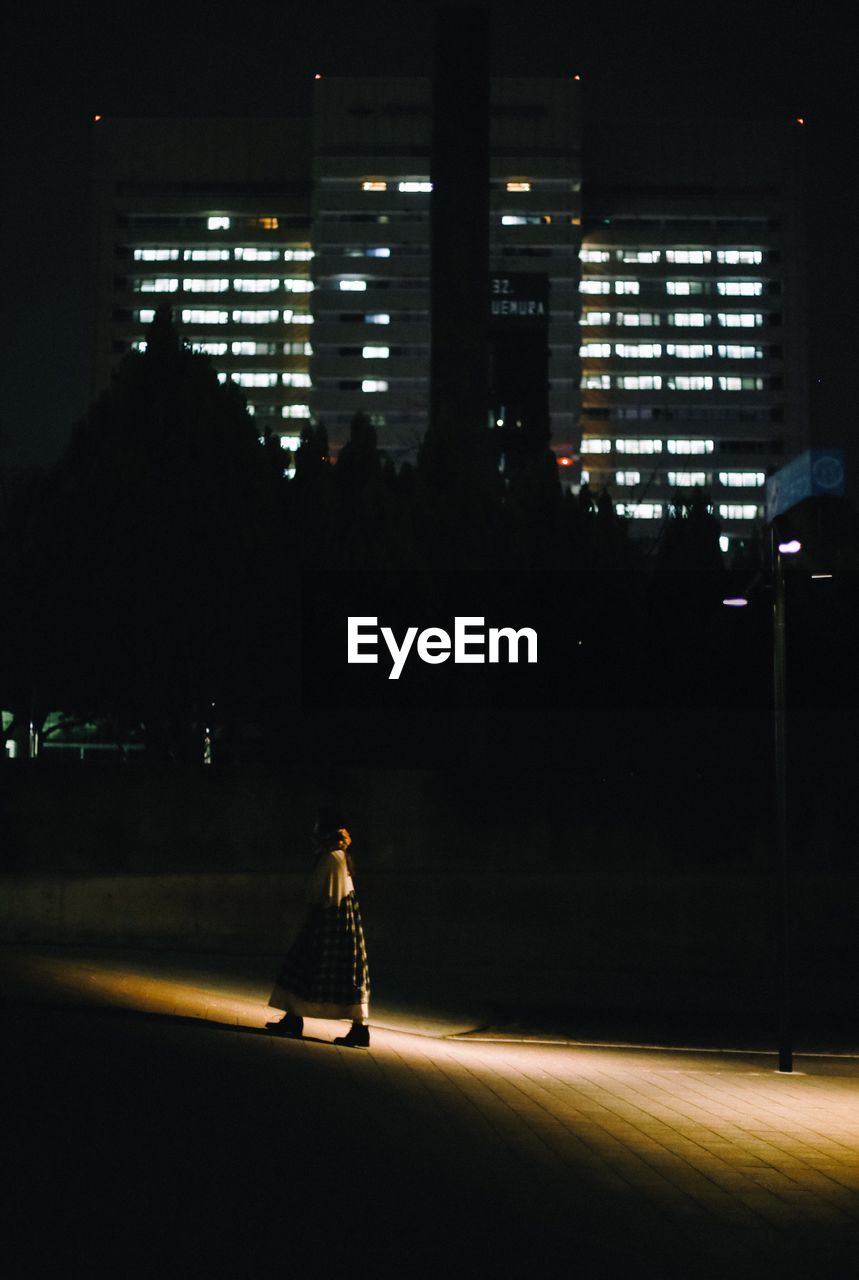 Woman walking on road in city at night