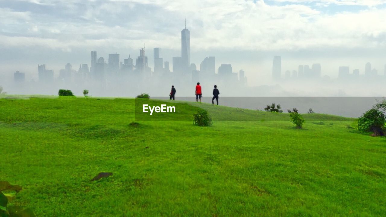 PEOPLE ON FIELD AGAINST SKY