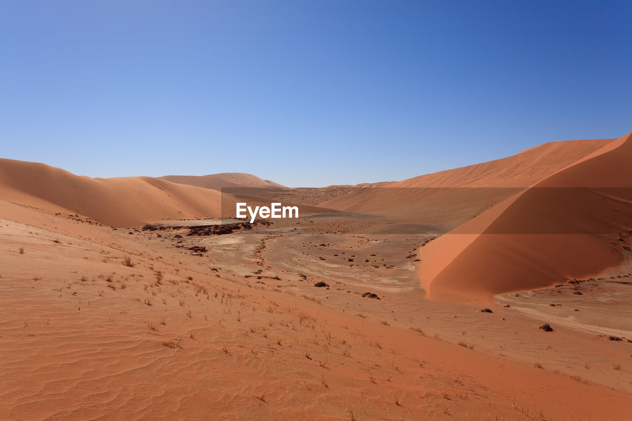 Scenic view of desert against clear blue sky