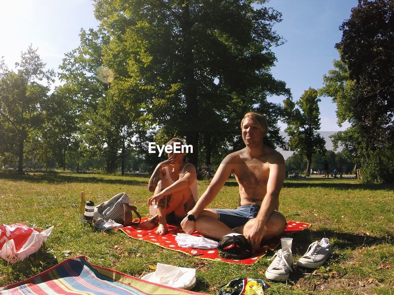 Portrait of man and woman sitting at park on sunny day