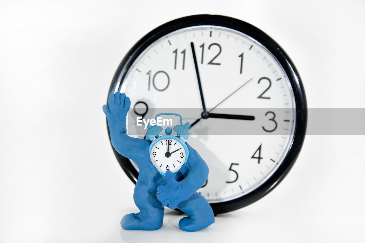CLOSE-UP OF CLOCK AGAINST WHITE WALL