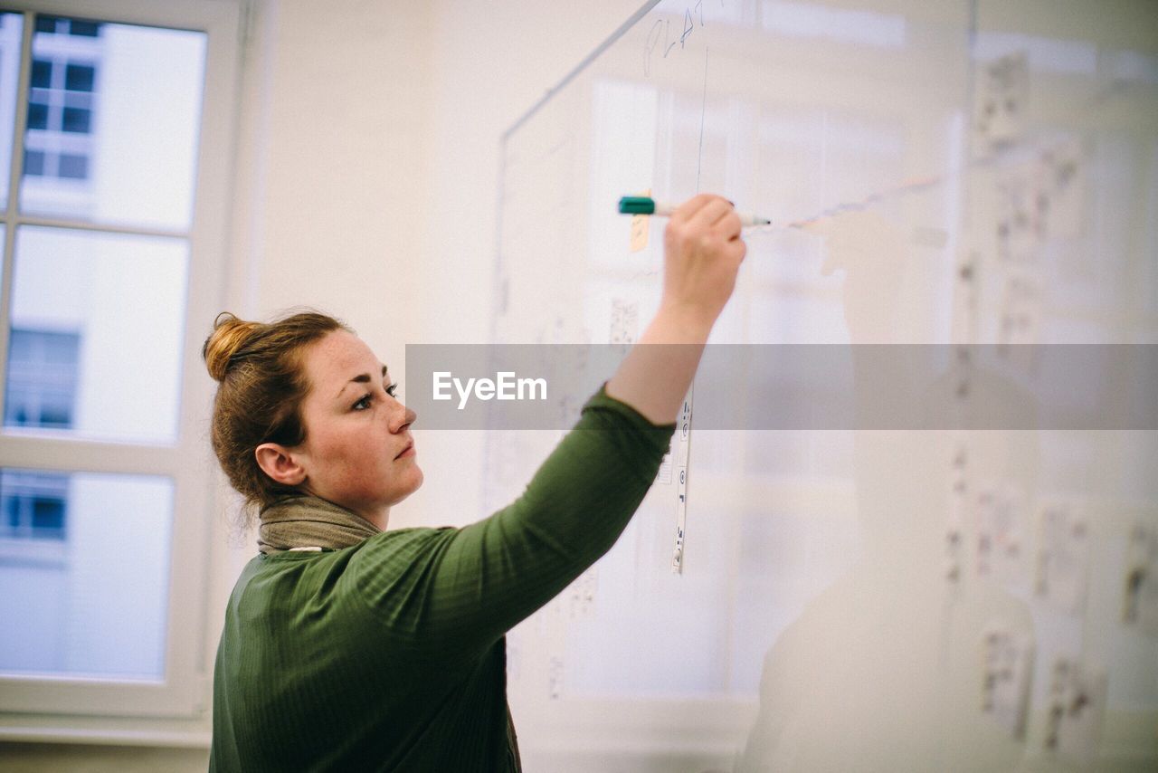 Teacher writing on whiteboard in classroom