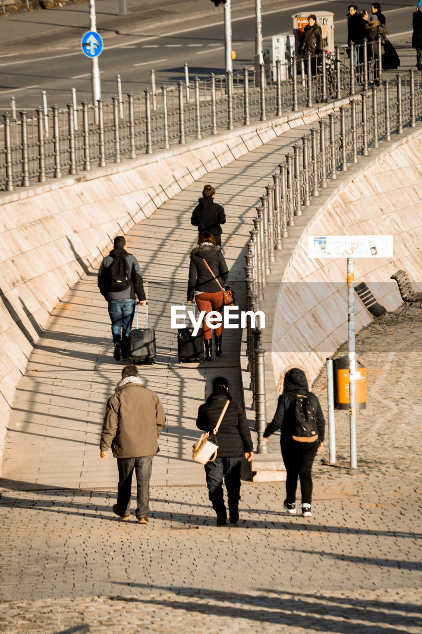 REAR VIEW OF PEOPLE WALKING ON ZEBRA CROSSING