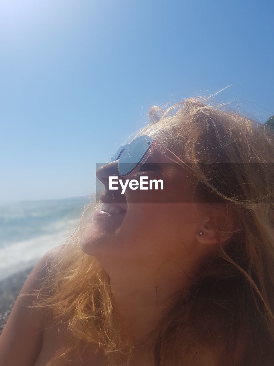 PORTRAIT OF WOMAN WEARING SUNGLASSES AGAINST CLEAR SKY