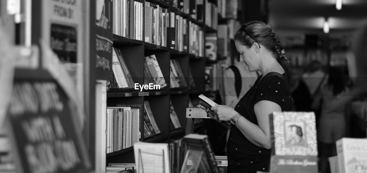 WOMAN STANDING IN FRONT OF A BOOKS