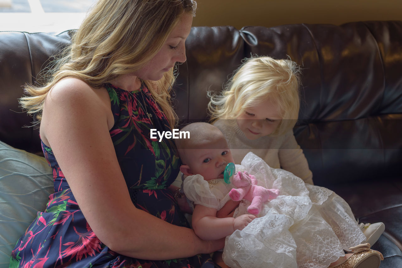 Mother with cute daughters sitting on sofa at home