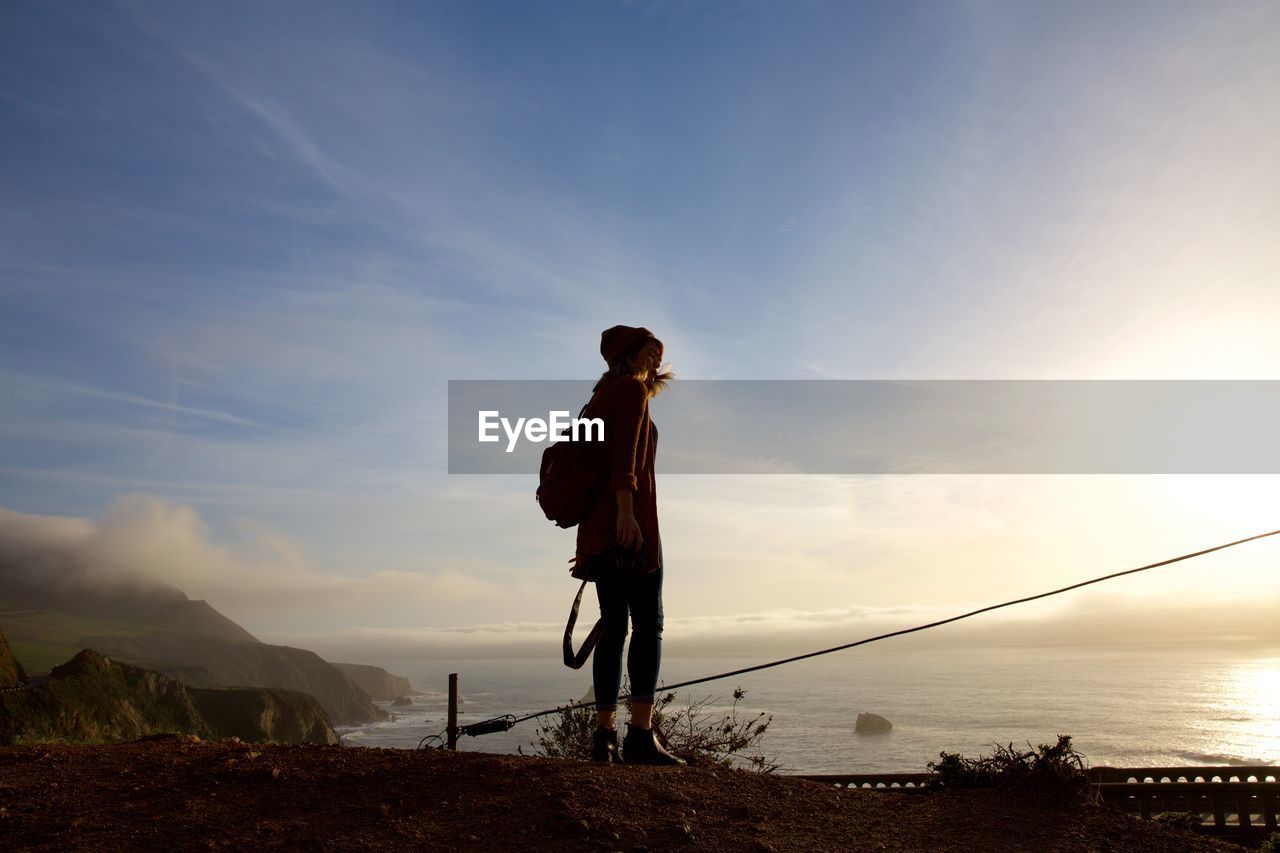 Low angle view of woman standing by sea against sky