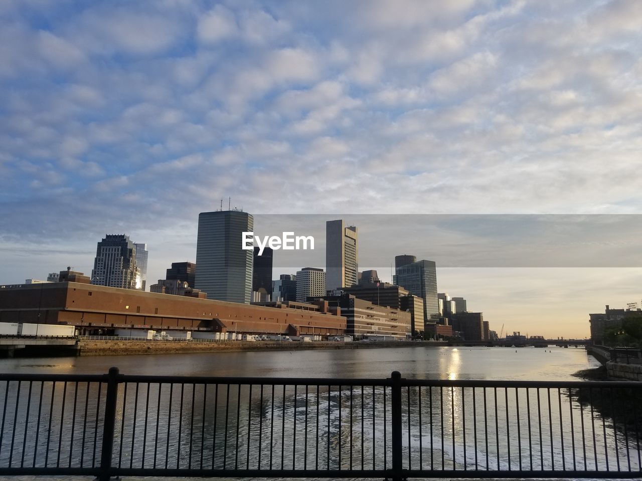 Modern buildings by river against sky in city