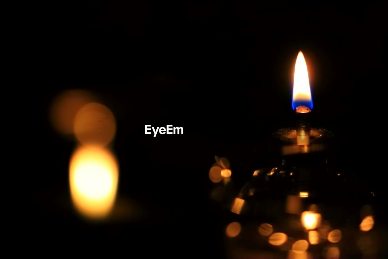 CLOSE-UP OF LIT CANDLE IN DARKROOM