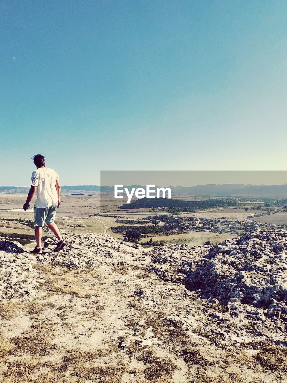 Man walking on rock against landscape and clear sky