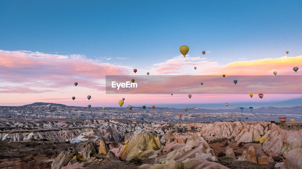 VIEW OF HOT AIR BALLOONS FLYING OVER ROCKS