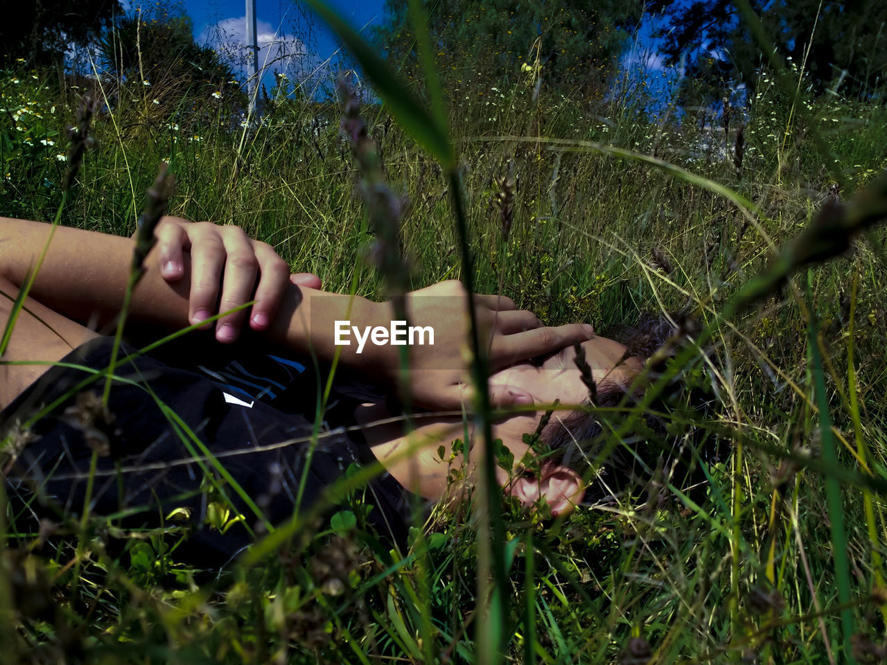 Teenage boy lying down on grassy field