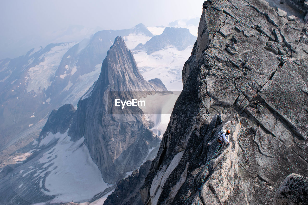 High angle view of young man climbing mountain during winter