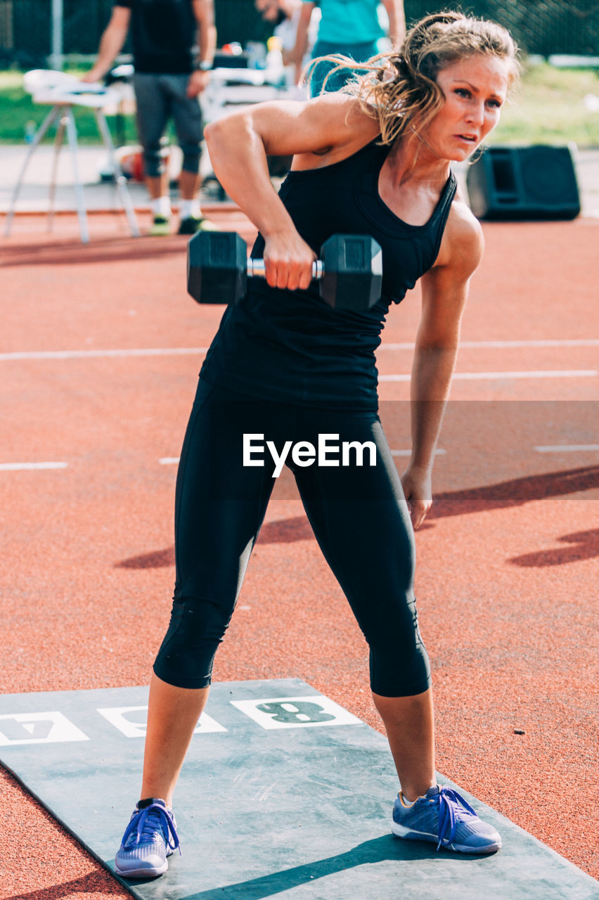 Woman lifting dumbbells on running track
