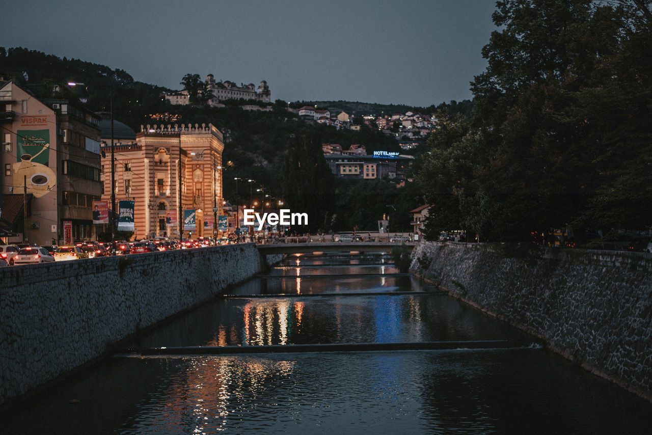 ARCH BRIDGE OVER RIVER AMIDST BUILDINGS IN CITY