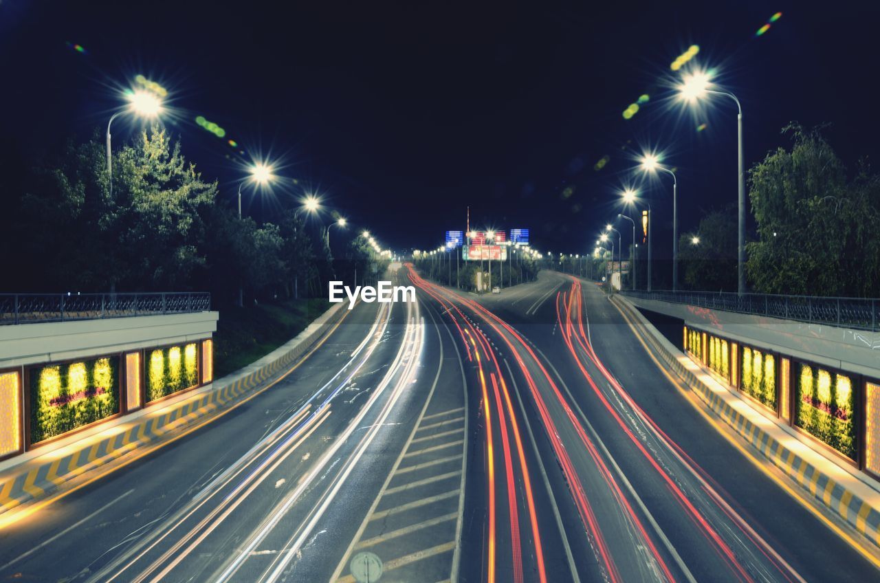 ILLUMINATED LIGHT TRAILS ON ROAD AT NIGHT