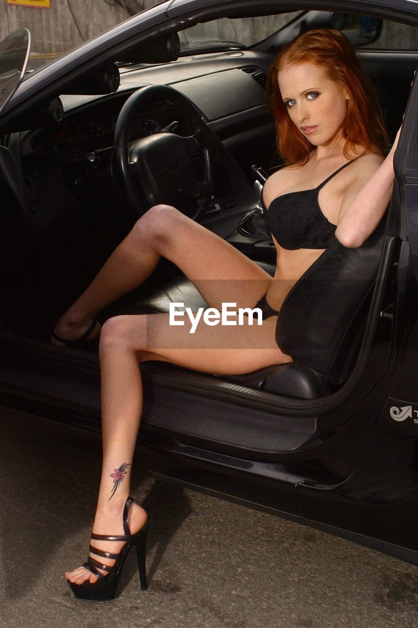 Side view portrait of beautiful seductive woman sitting in car