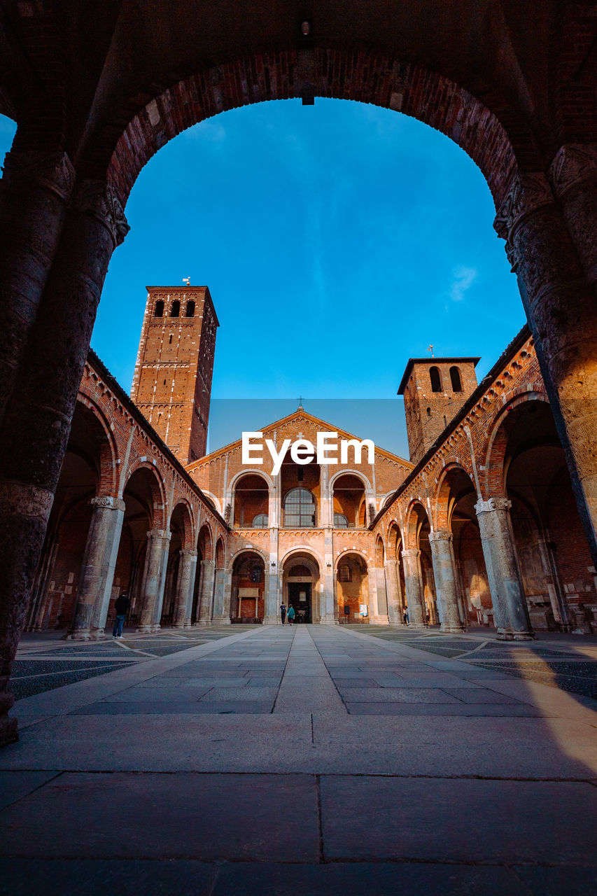 Wide view of the basilica of sant'ambrogio with arcade with people walking