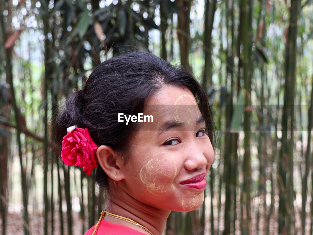 Close-up portrait of a smiling young tribal woman in forest